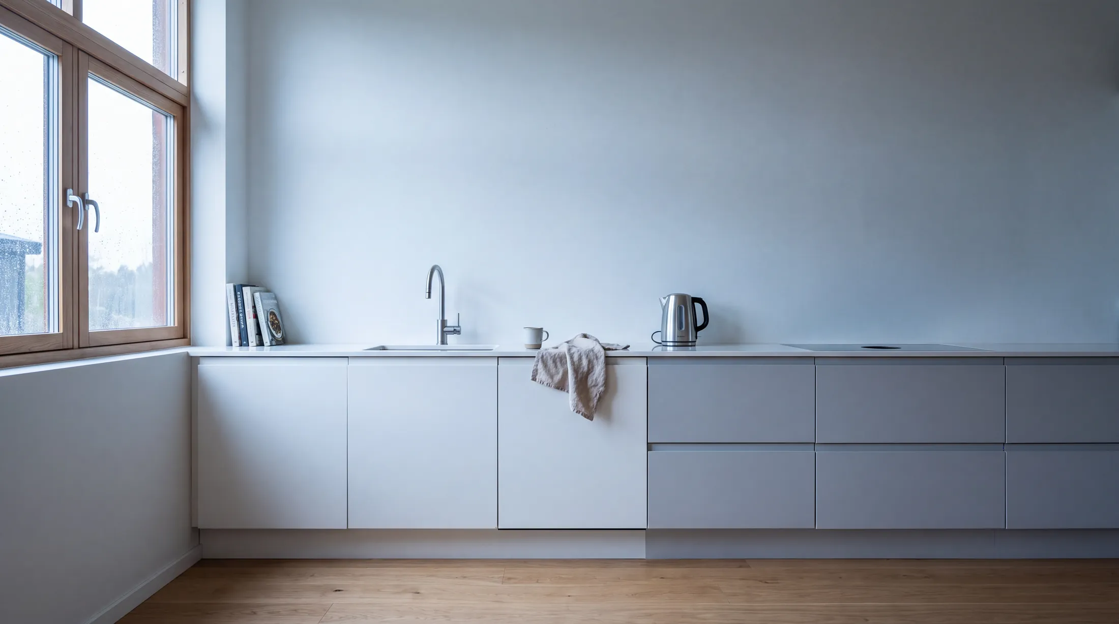 Ljust minimalistiskt kök med träluckor och vit bänkskiva